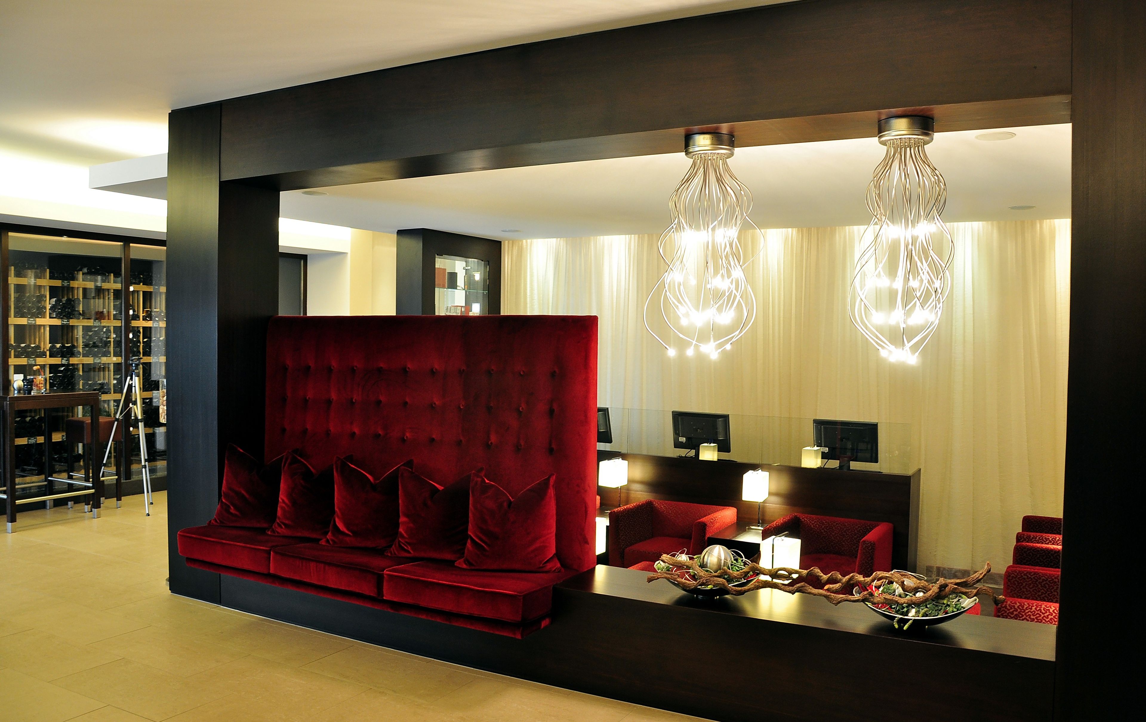 Un vestíbulo de hotel moderno con un sofá rojo, un mostrador de recepción y una exhibición de zapatos.
