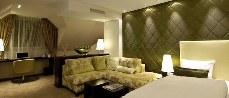 A hotel room with a bed, a sofa, a desk, and a chair.