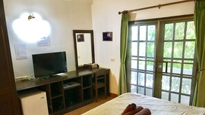 A hotel room with a bed, a desk with a computer, a TV, and a window with curtains. - Bon Ca Va (Chiang Mai)