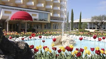 Un hotel con piscina rodeado de tulipanes de colores, una fuente y un paraguas rojo.