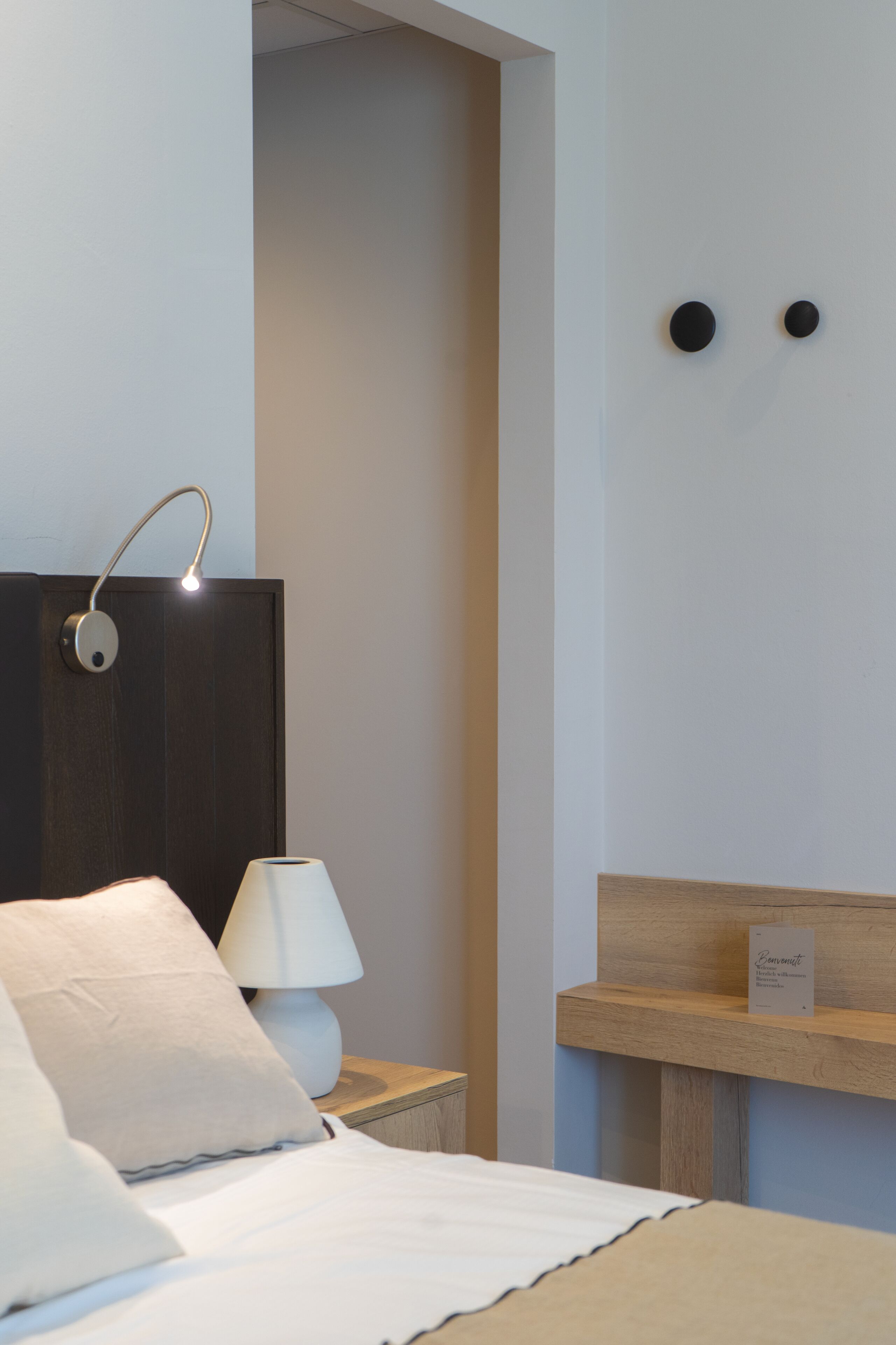 A modern bedroom with a bed, bedside lamp, and a nightstand.