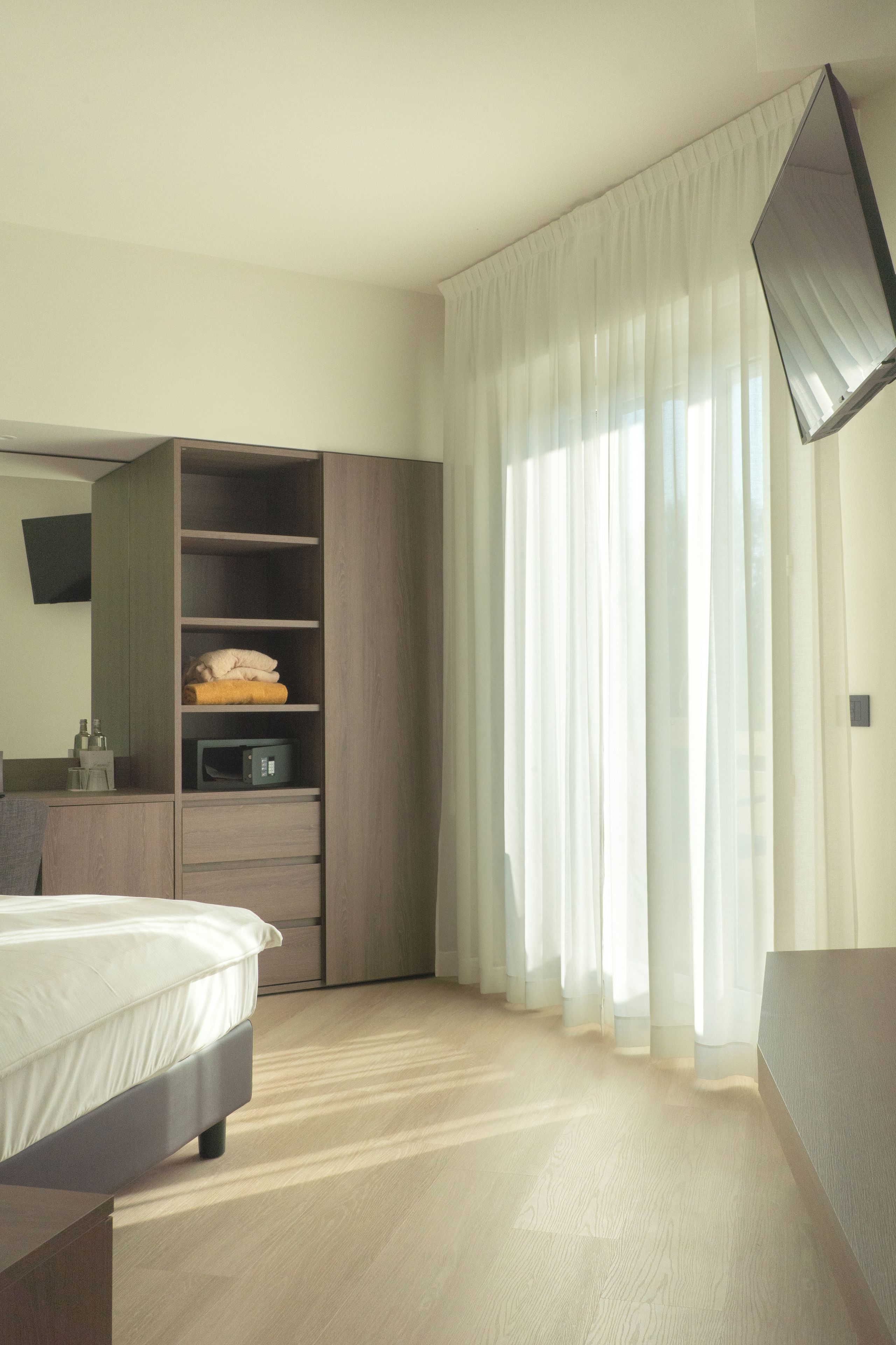 A hotel room with a bed, a wardrobe, a mirror, and a television.