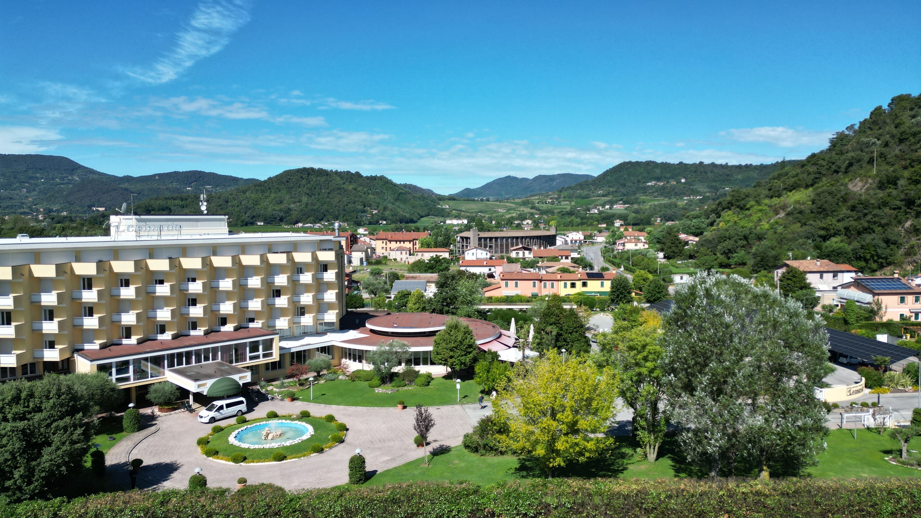 Un hotel con un patio central, rodeado de exuberante vegetación y montañas al fondo.