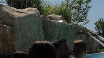 A swimming pool with clear water, surrounded by rocks and greenery.
