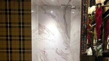 A bathroom with marble walls, a wooden floor, and a mirror with a decorative frame.