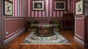 A room with a drum table, green armchairs, a patterned rug, and framed pictures on the wall. - Residenza Borsari (Verona)