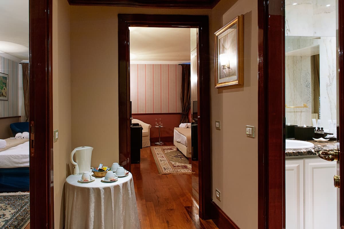 A hotel corridor with a table set for breakfast, a bed, and a bathroom visible in the background.