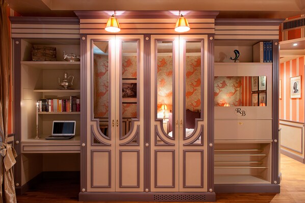 Een kamer met een bureau, een laptop en een garderobe met spiegel.