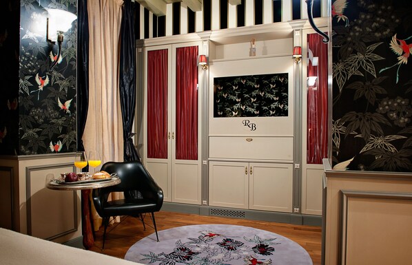 Una habitación con una mesa de comedor dispuesta para el desayuno, una silla negra y un muro decorativo con estampado floral.