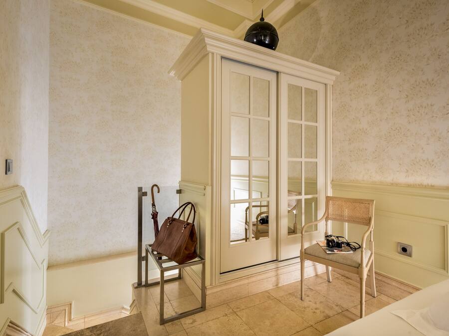 Quarto com um espelho grande, uma cadeira, uma mesinha e um guarda-roupa.