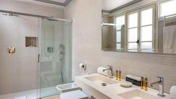 Un baño moderno con ducha de vidrio, tocador doble y un espejo grande.
