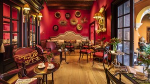 A room with a red wall, a tufted sofa, and a wooden ceiling. - Hotel Boutique Casa del Poeta Sevilla (Seville)