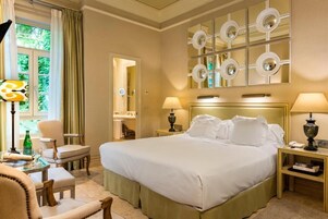 Una habitación de hotel con una cama grande, dos mesitas de noche, un espejo y una ventana con cortinas.