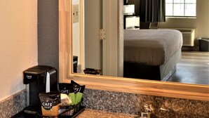 A hotel bathroom with a sink, mirror, and a coffee maker. - Lake View Inn (Granbury)