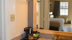 A hotel bathroom with a granite countertop, a sink, a mirror, and a coffee maker. - Lake View Inn (Granbury)