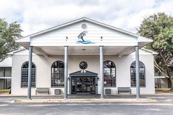 A building with a white facade, large arched windows, and a central entrance with a decorative emblem.