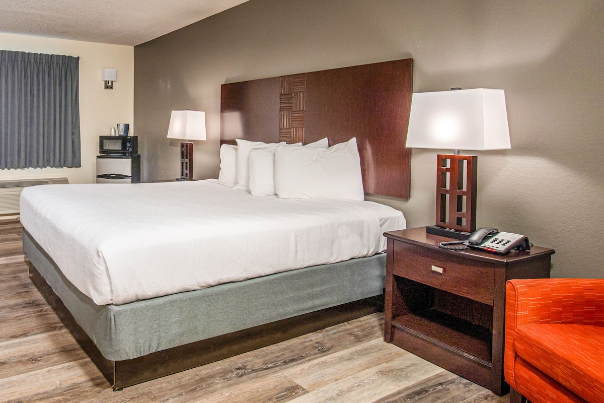 A hotel room with a large bed, bedside lamps, a desk with a phone, and a chair.