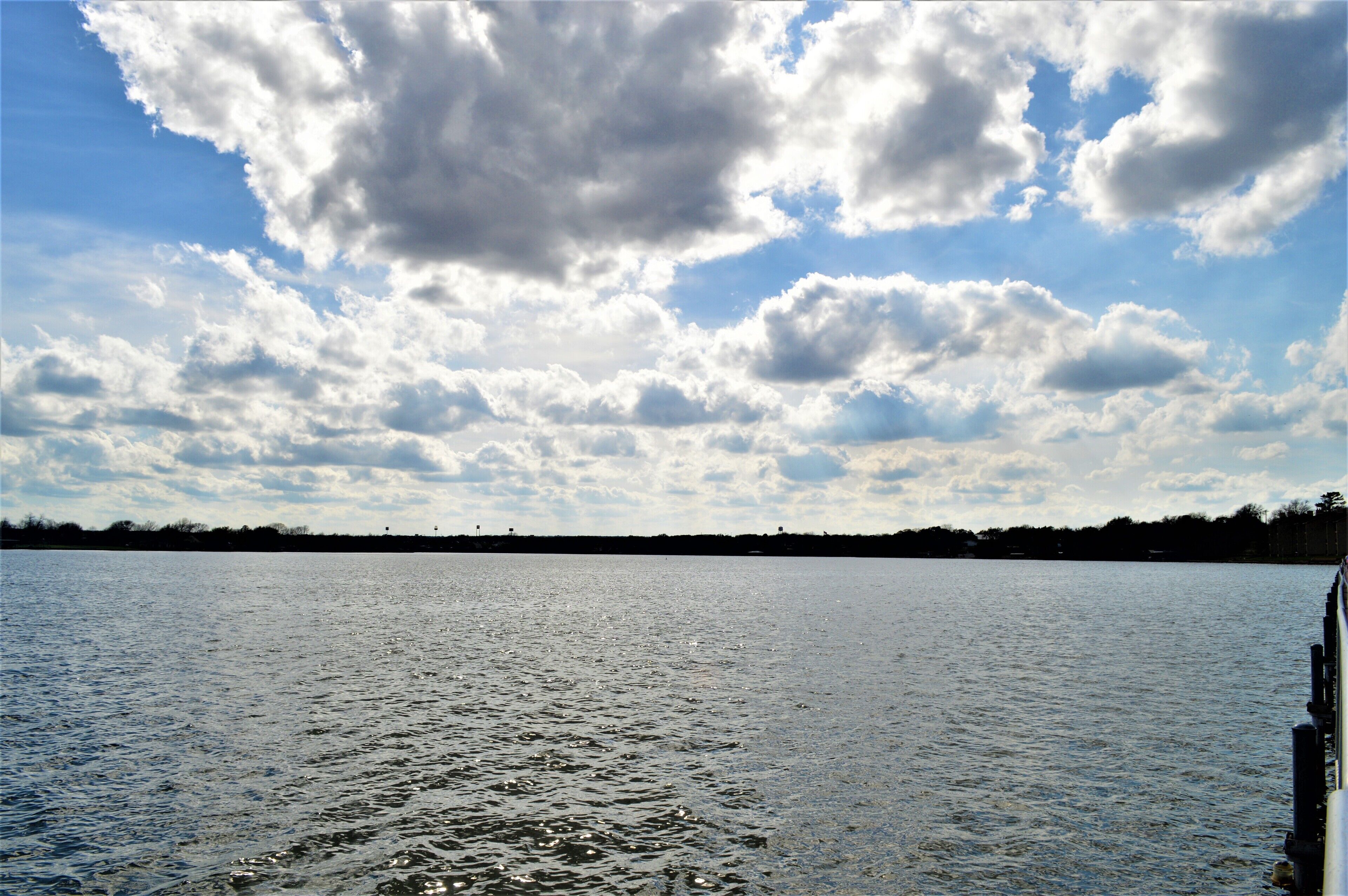 A calm body of water with a distant shoreline and a partly cloudy sky.