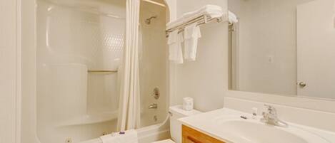 A bathroom with a bathtub, toilet, sink, and a mirror.