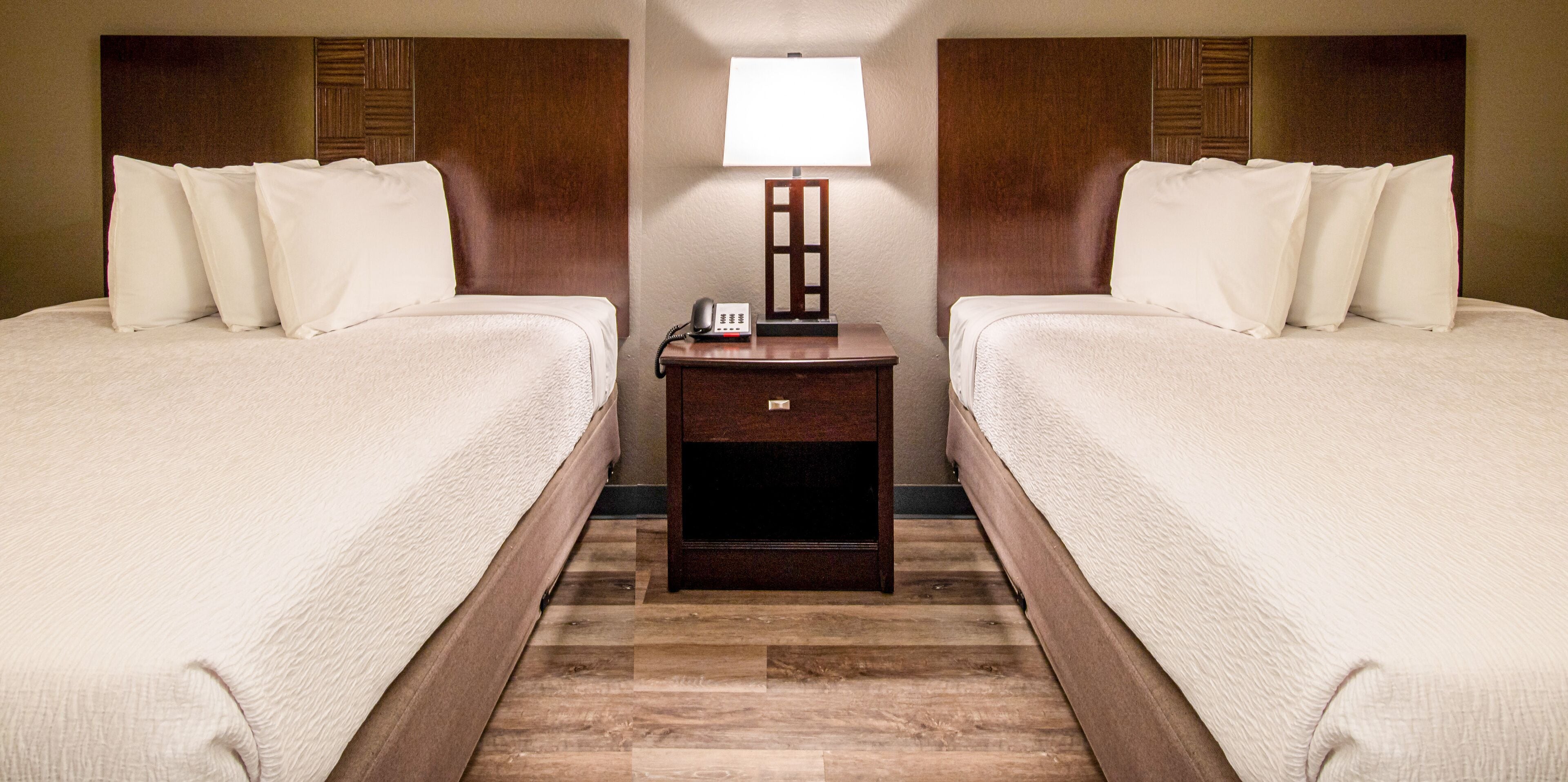 Une chambre d’hôtel avec deux lits, une table de chevet avec une lampe et un téléphone.