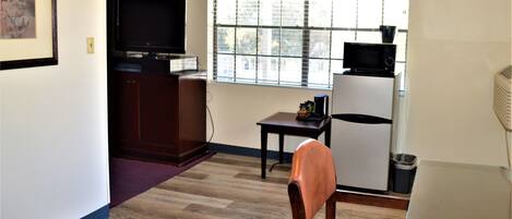 A compact living space with a television, a microwave, and a refrigerator.