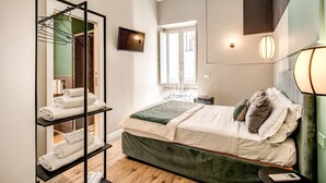 Une chambre avec un lit, une étagère avec des serviettes, une télévision et une fenêtre.
