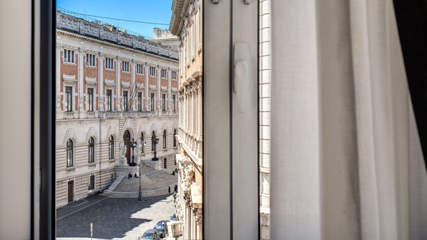 Une vue d’une cour intérieure dotée d’une architecture classique, avec un escalier central et une statue.