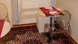 Une pièce avec une table à manger dressée pour deux personnes, une vue dégagée à travers un portail orné et une lampe fixée au mur.