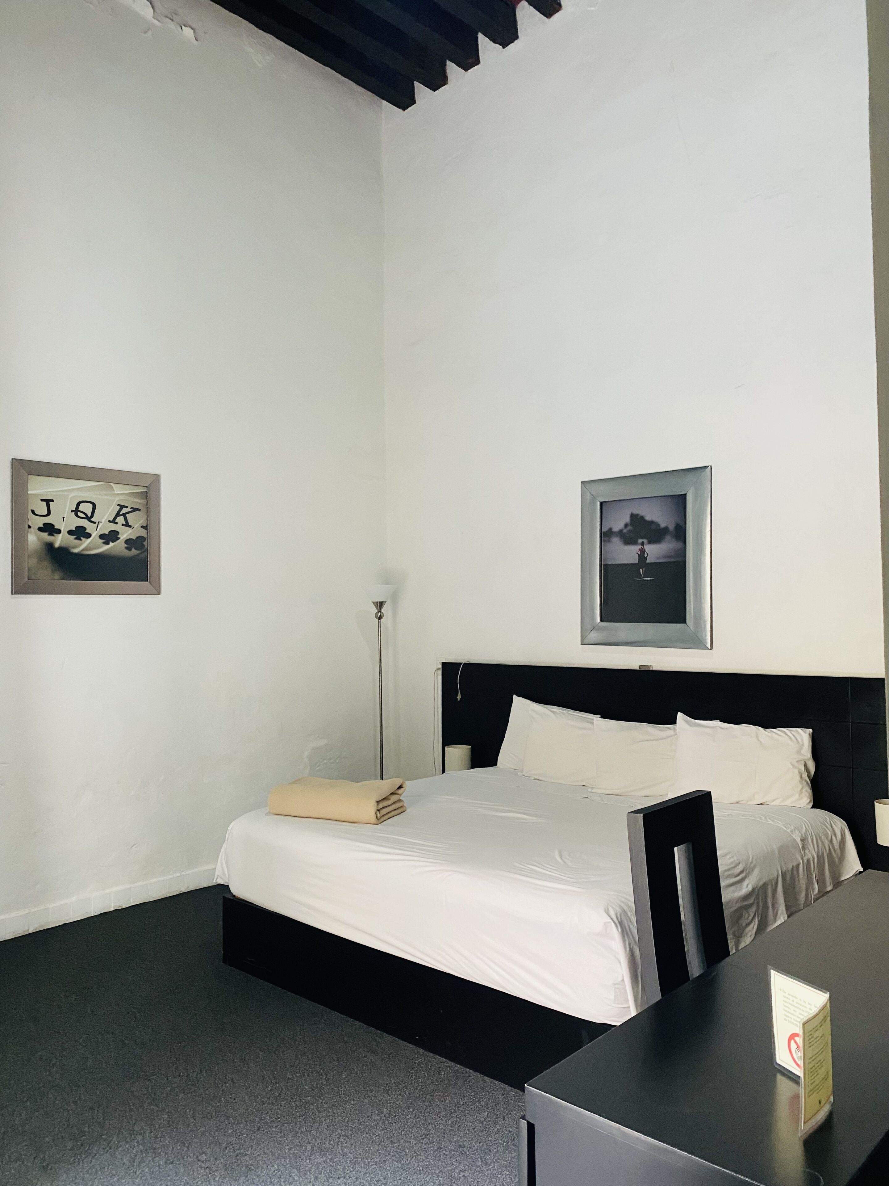 Un dormitorio con una cama, un escritorio y dos cuadros en la pared.