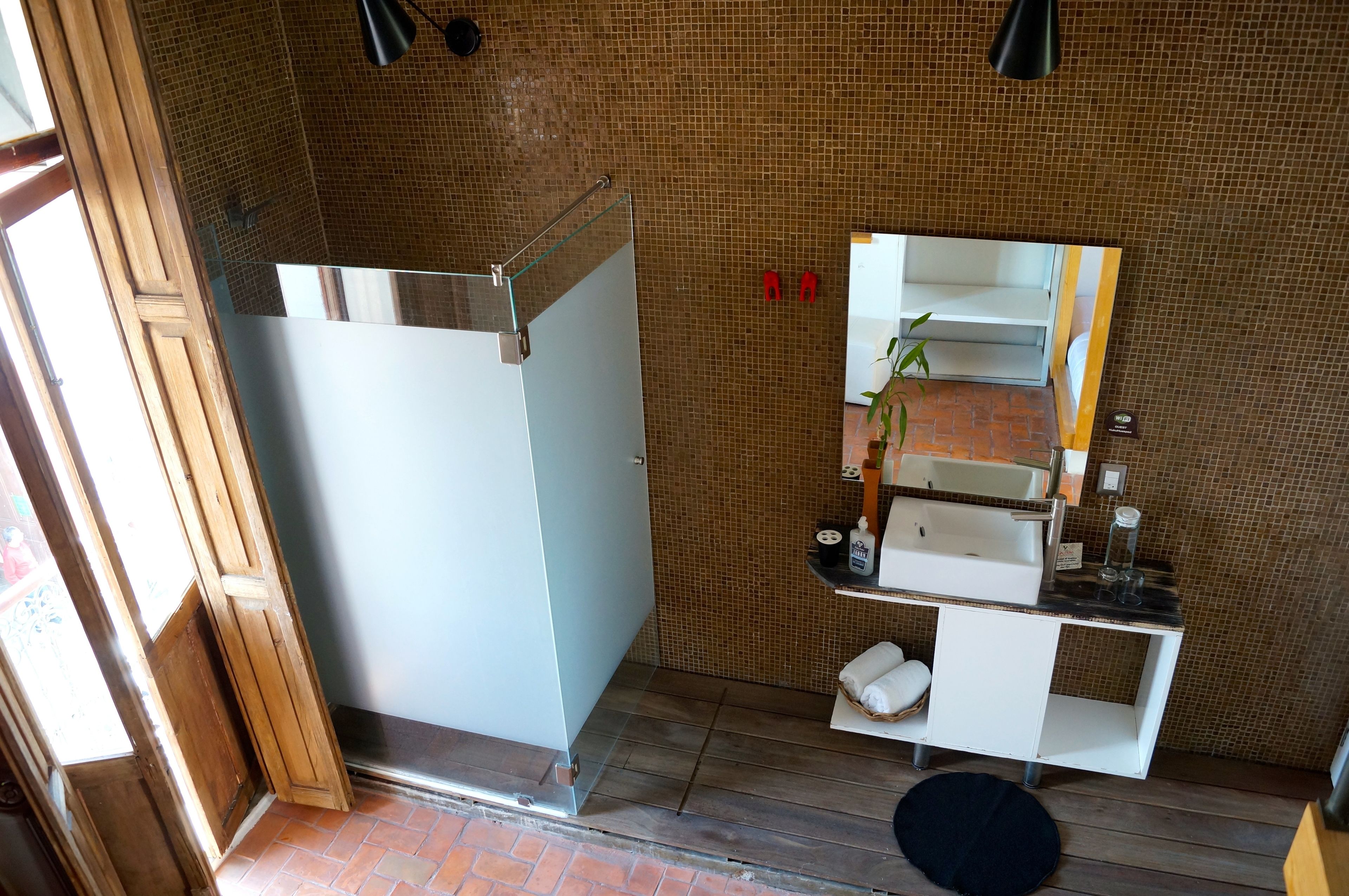 A bathroom with a shower, a sink, a mirror, and a towel rack.