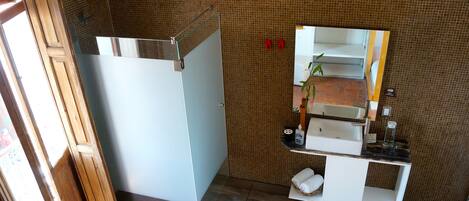 A bathroom with a shower, a sink, a mirror, and a towel rack.