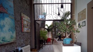 A cozy hotel lobby with a patterned floor, a seating area with a bench, and a large plant. - Kuku Rukú Querétaro (Querétaro)
