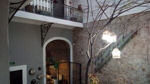 A courtyard with a wooden bench, a potted plant, and a staircase with a metal railing. - Kuku Rukú Querétaro (Querétaro)