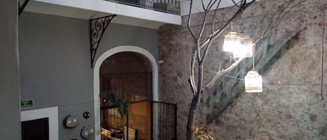 Une cour avec un banc en bois, un pot de fleurs et un escalier doté d’une rampe en métal.