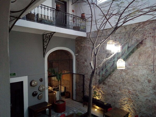 A courtyard with a wooden bench, a potted plant, and a staircase with a metal railing.