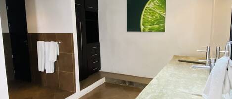 Un baño moderno con un espejo grande, un lavamanos con encimera y una zona de ducha.
