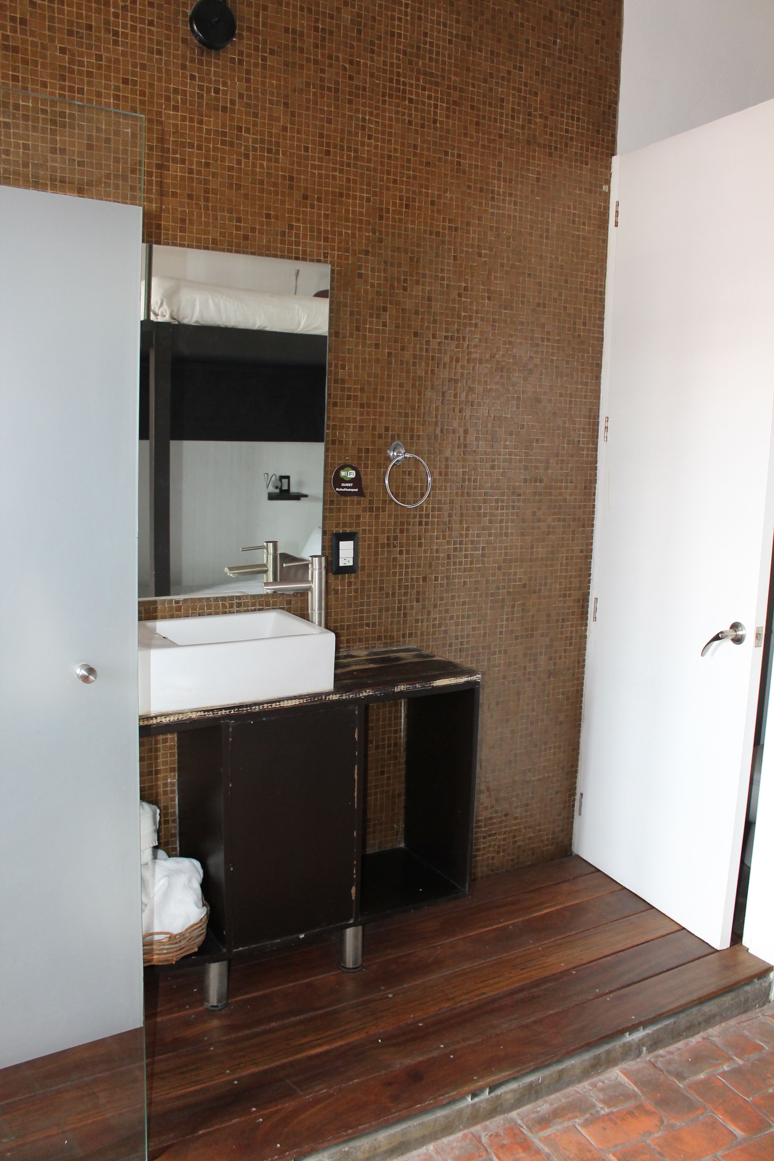 Un baño con lavamanos blanco, un espejo, toallero y una puerta.