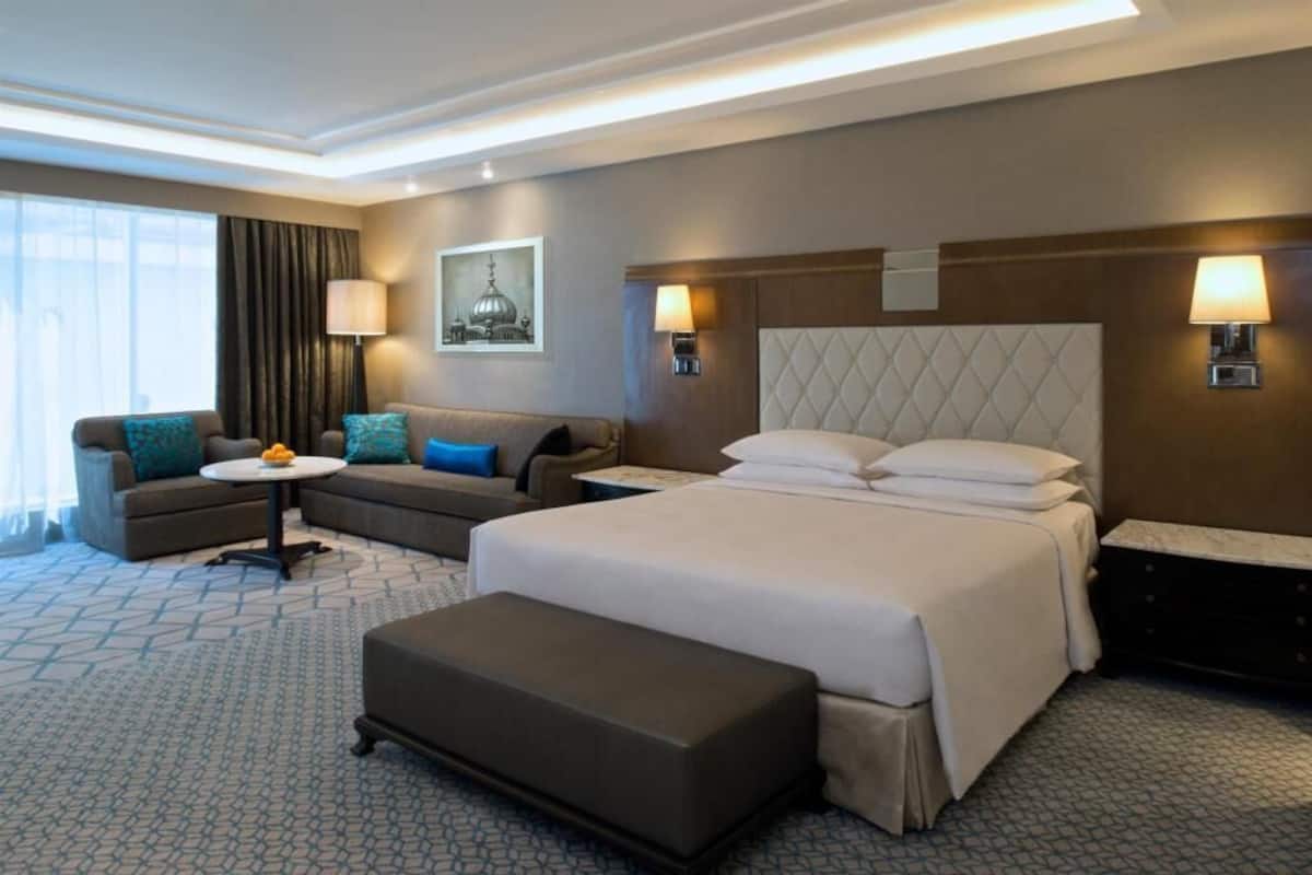 Una habitación de hotel con una cama grande, un sofá, una mesita y un banco.