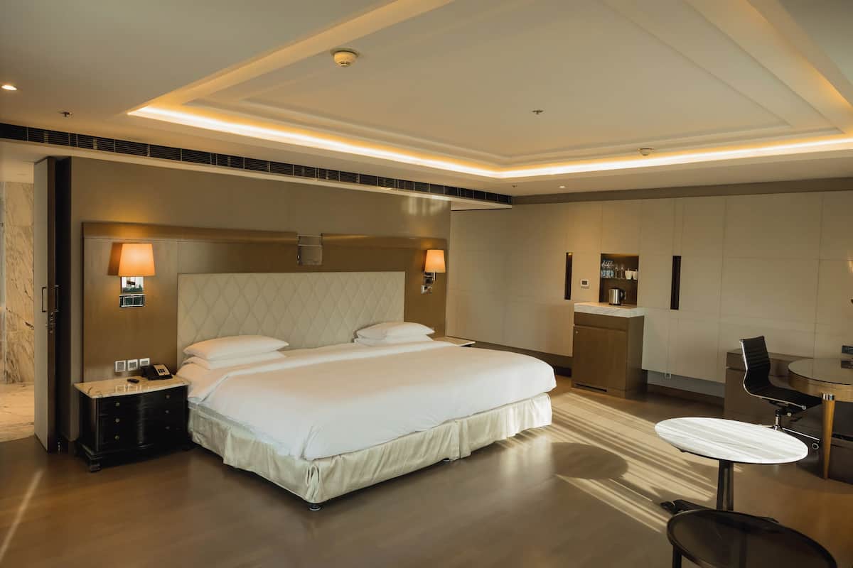 Una habitación de hotel moderna con una cama grande, lámparas de noche, un escritorio y una silla.