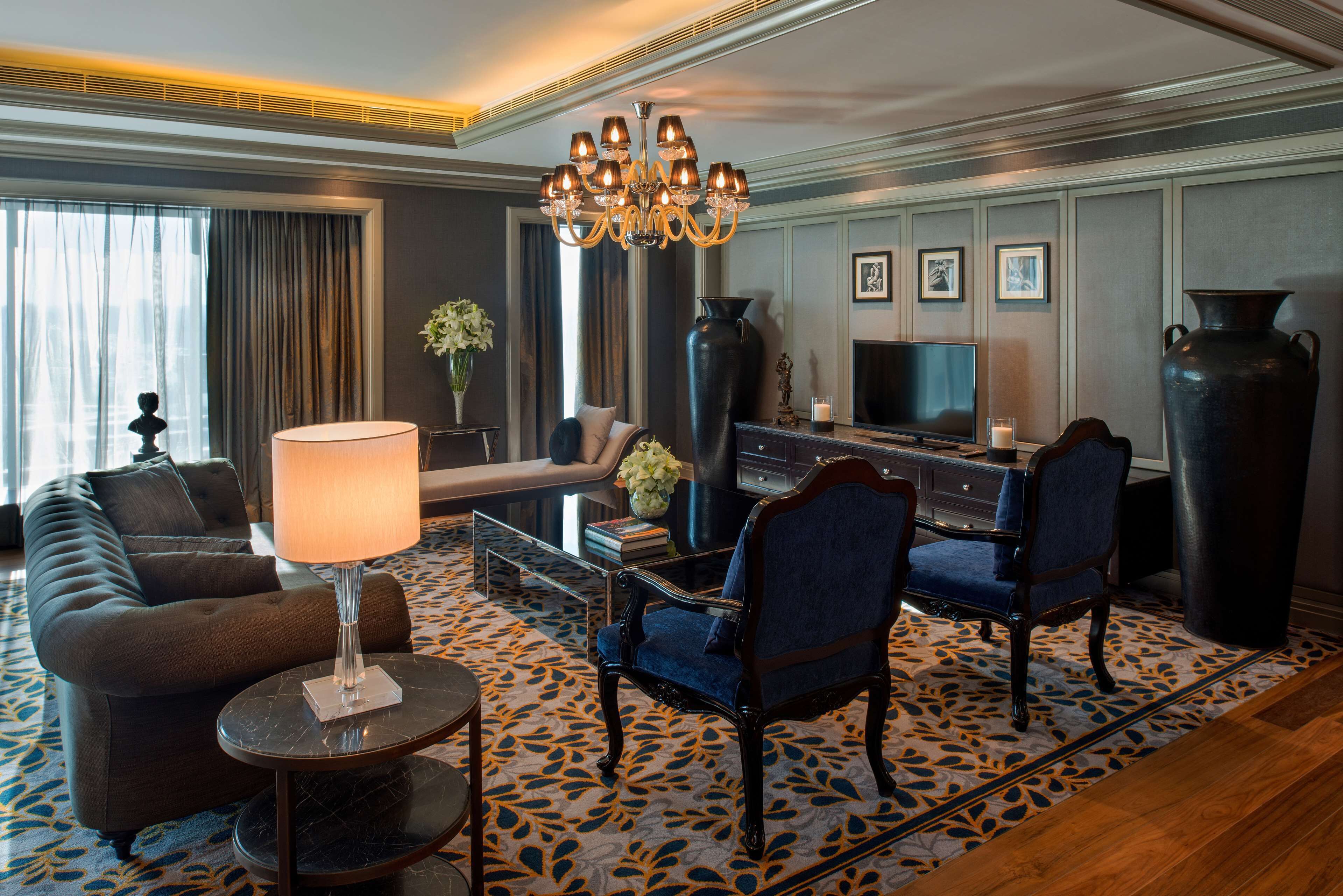 Une chambre d’hôtel moderne, équipée d’un canapé, de fauteuils, d’une télévision et d’un grand vase.
