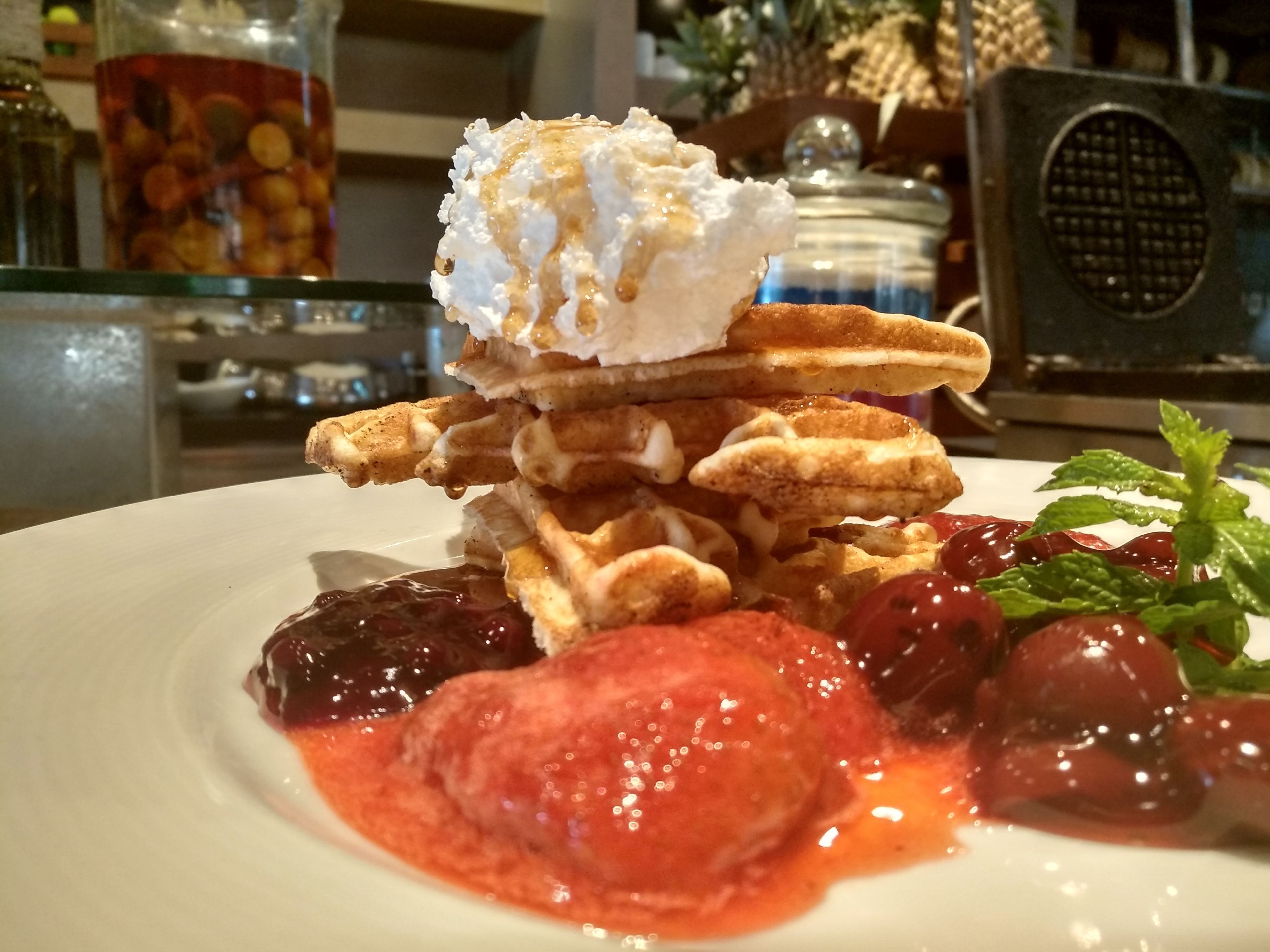 Un plato de waffles con crema batida y fruta.