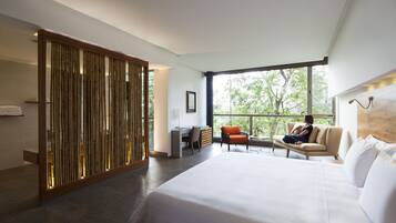 A modern hotel room with a large bed, a desk, and a seating area by a window.