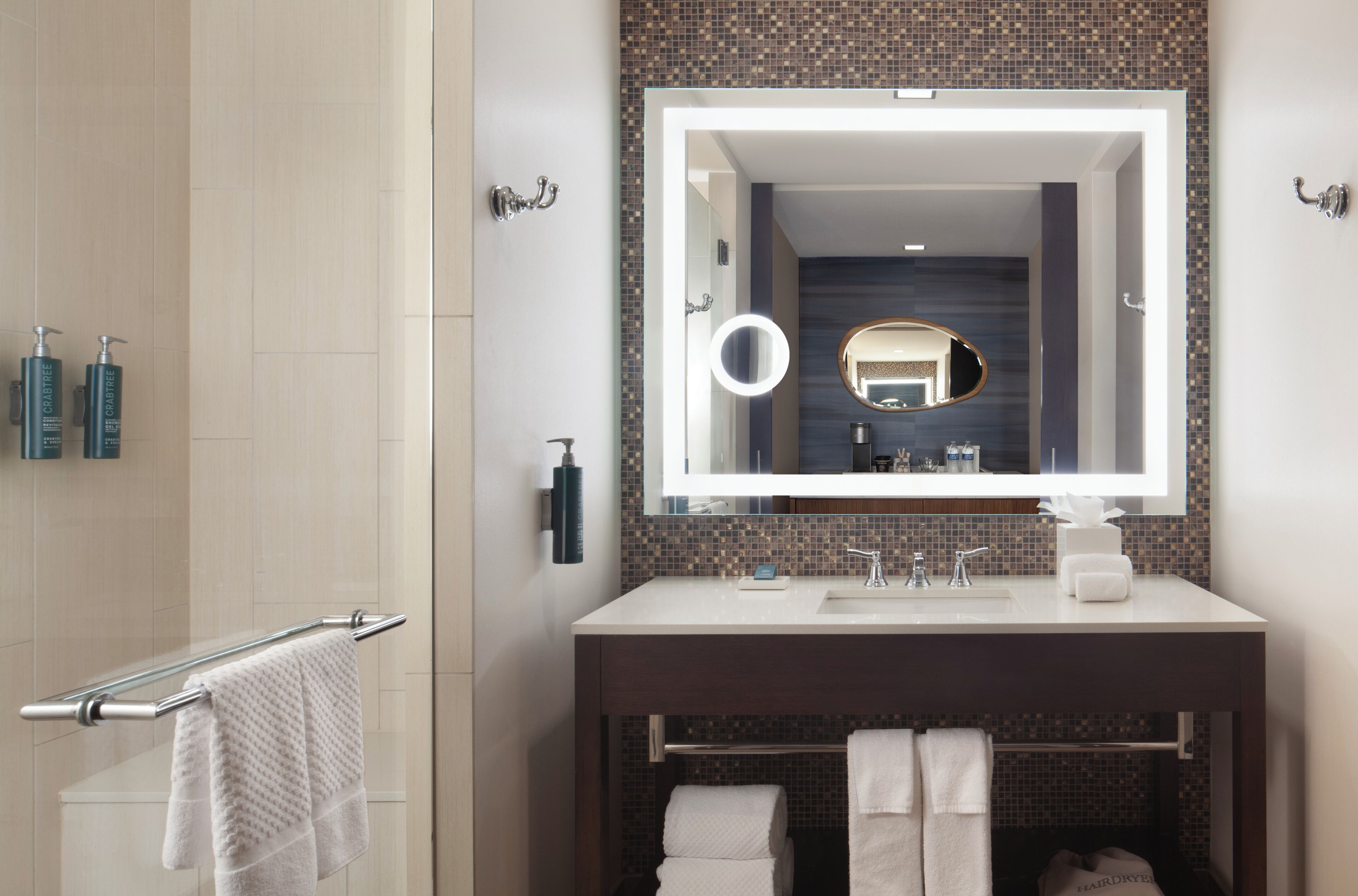 A modern bathroom with a large mirror, a towel rack, and a sink.
