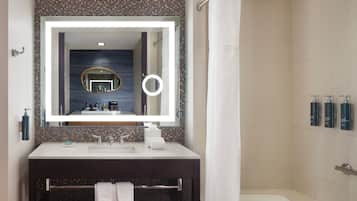 Une salle de bain avec un grand miroir, une baignoire, un meuble-lavabo et un porte-serviettes.
