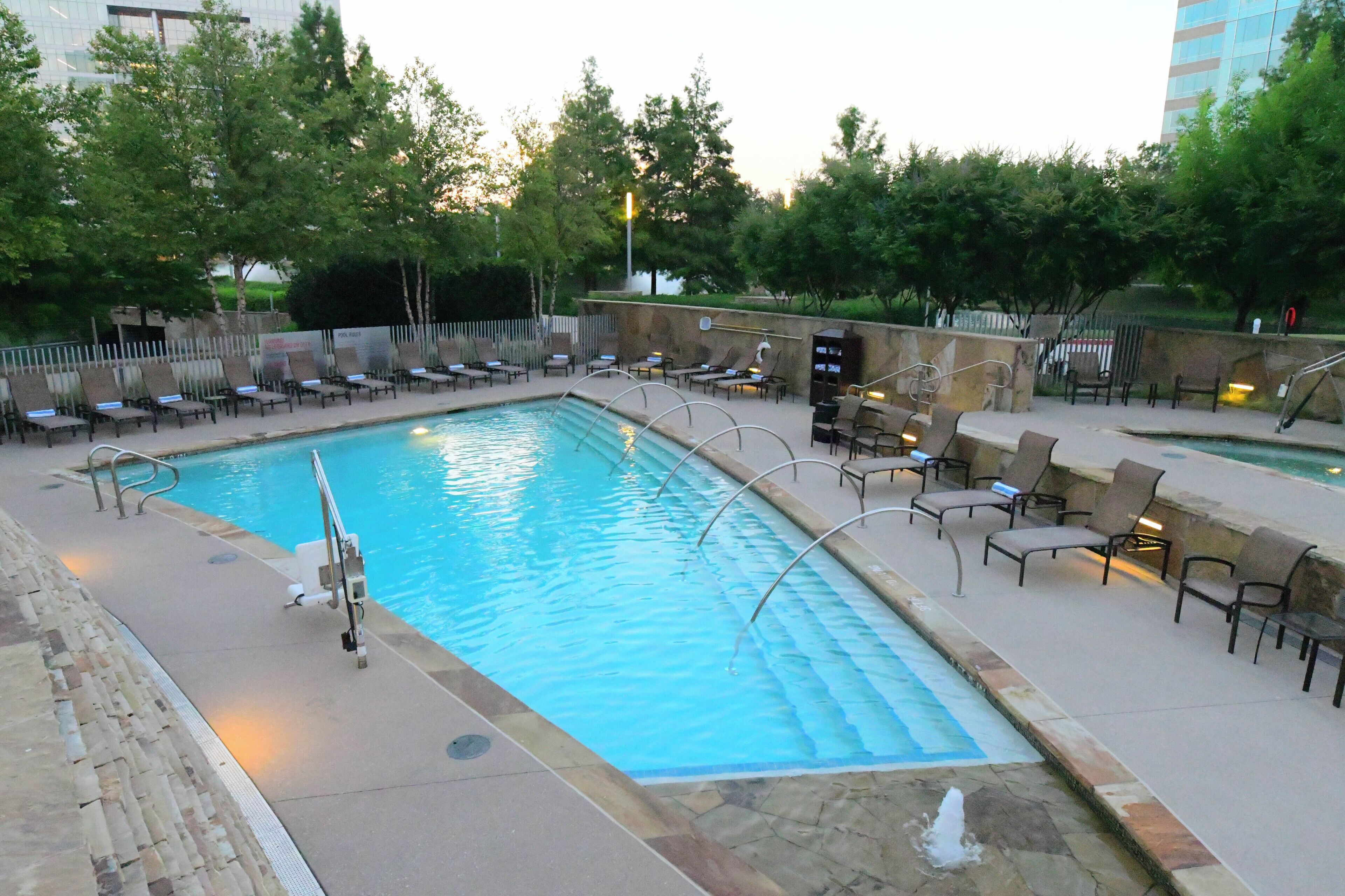 A swimming pool with lounge chairs and a stone wall.