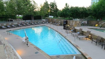A swimming pool with lounge chairs and a stone wall.