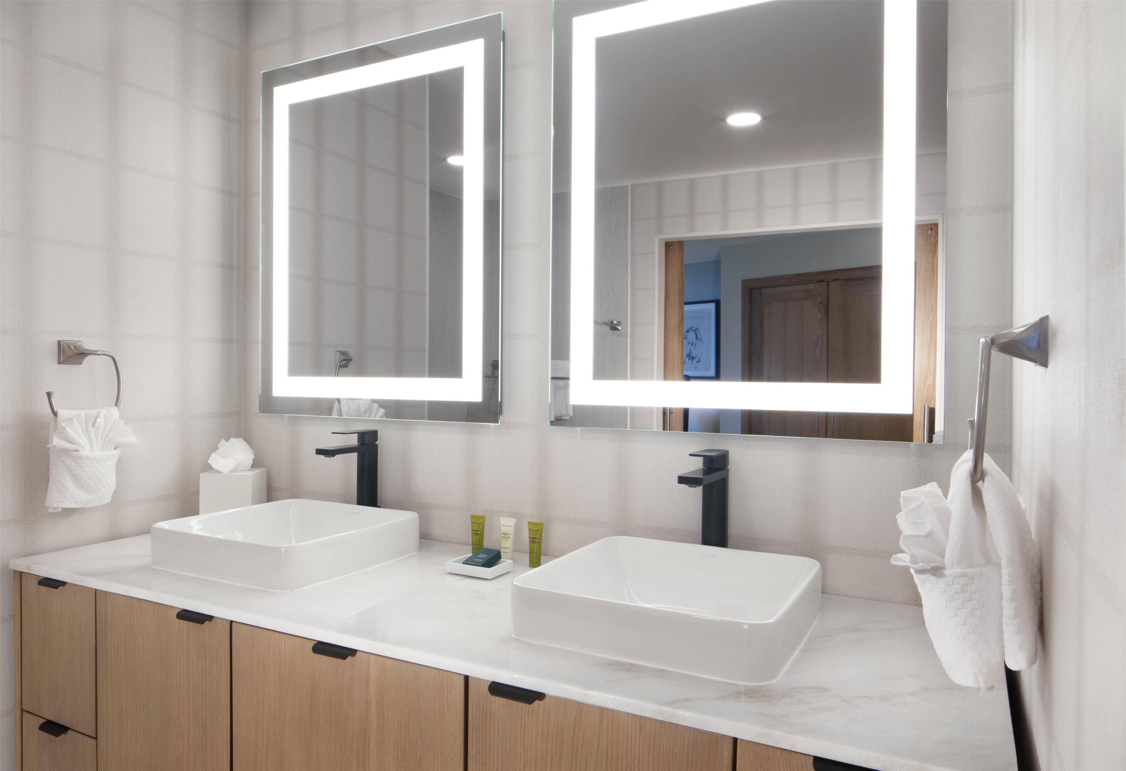 A bathroom with two sinks, a mirror, and a towel rack.