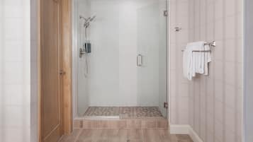 Un baño moderno con cabina de ducha de vidrio, suelo de madera y un perchero para toallas.