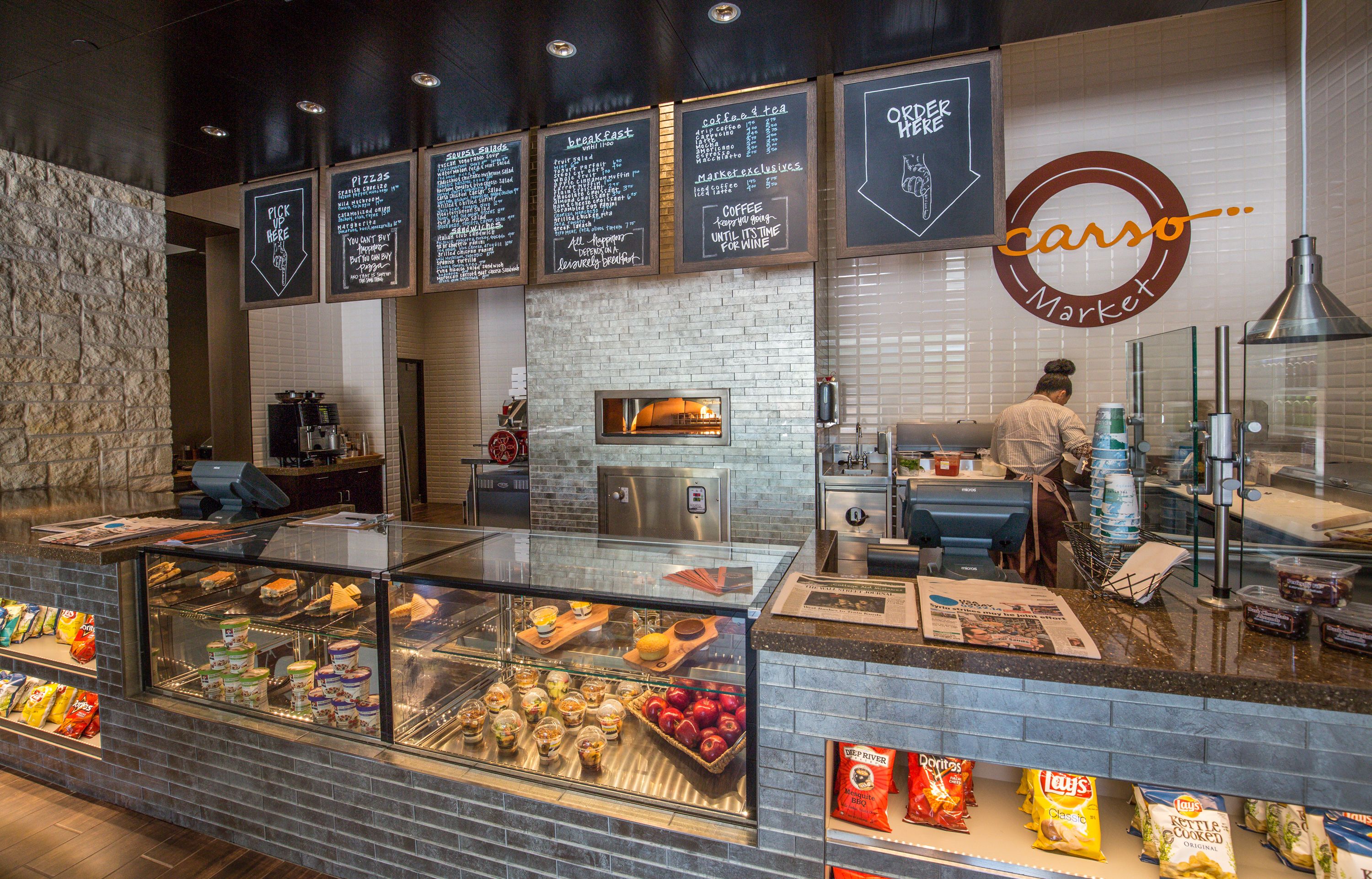 A food counter with a glass display case, a coffee machine, and a chalkboard menu.
