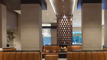 A modern lobby with leather seating, a central fireplace, and a view of the outdoors.